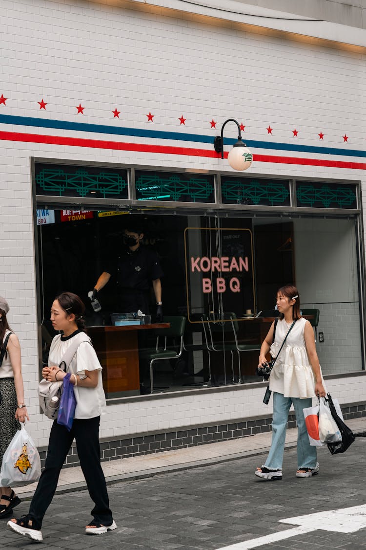 Women Walking Near Restaurant Window