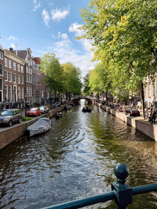 Free Charming view of a canal in Amsterdam with boats and classic architecture under a sunny sky. Stock Photo