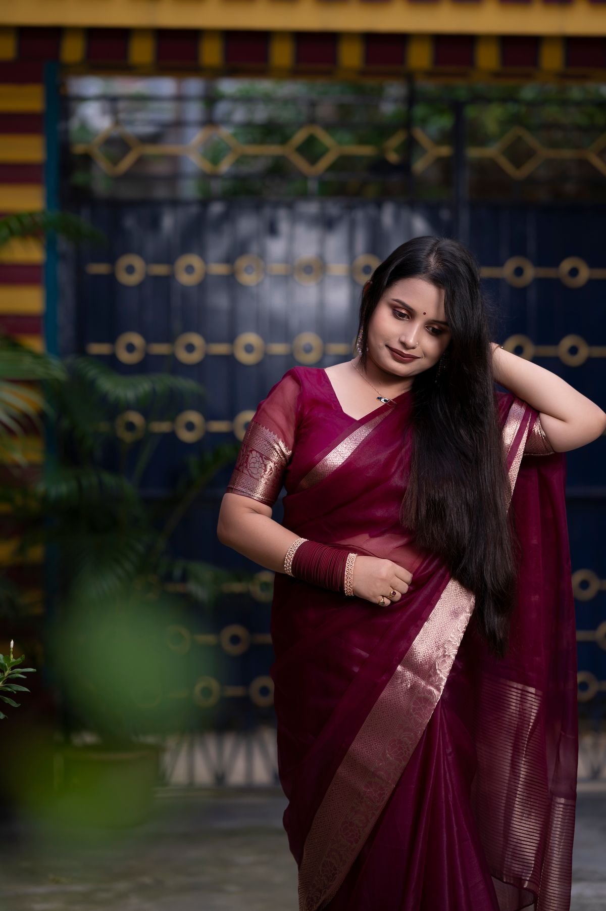 Woman in a royal maroon silk saree with a gold border