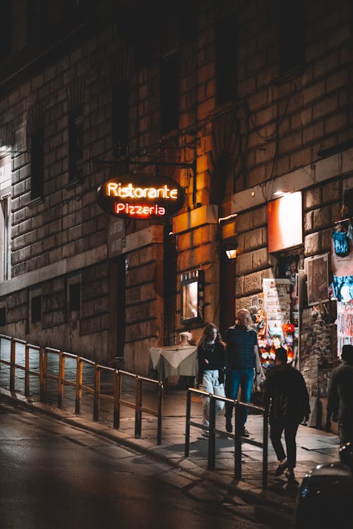 People Walking near Pizzeria at Night