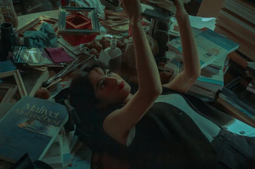 Woman in Gray Vest Lying on the Floor among Books