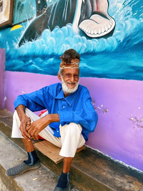Smiling Elderly Man Sitting by a Wall 