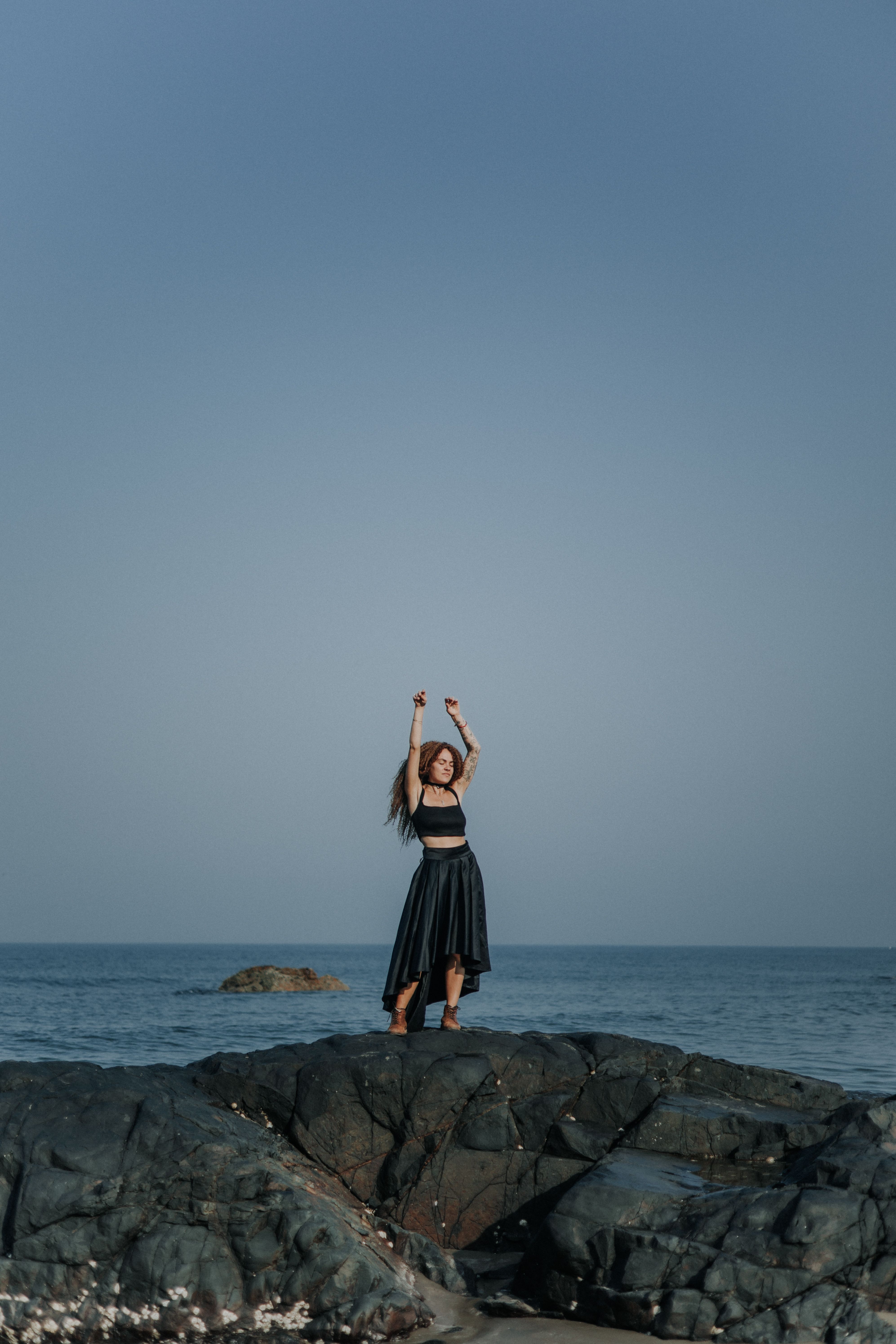 black dress beach photoshoot Elegant woman in black dress walking on beach outdoors, brown hair - Stock Photo