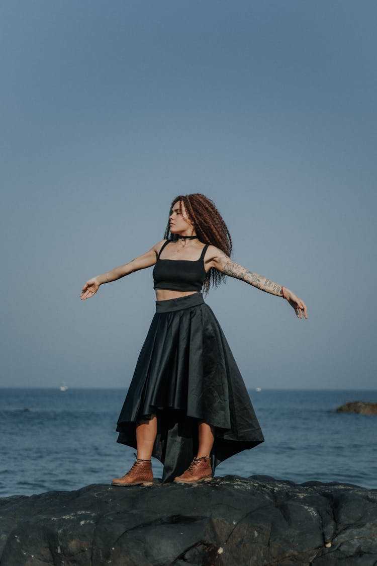 Woman Posing In Black Dress On A Beach 