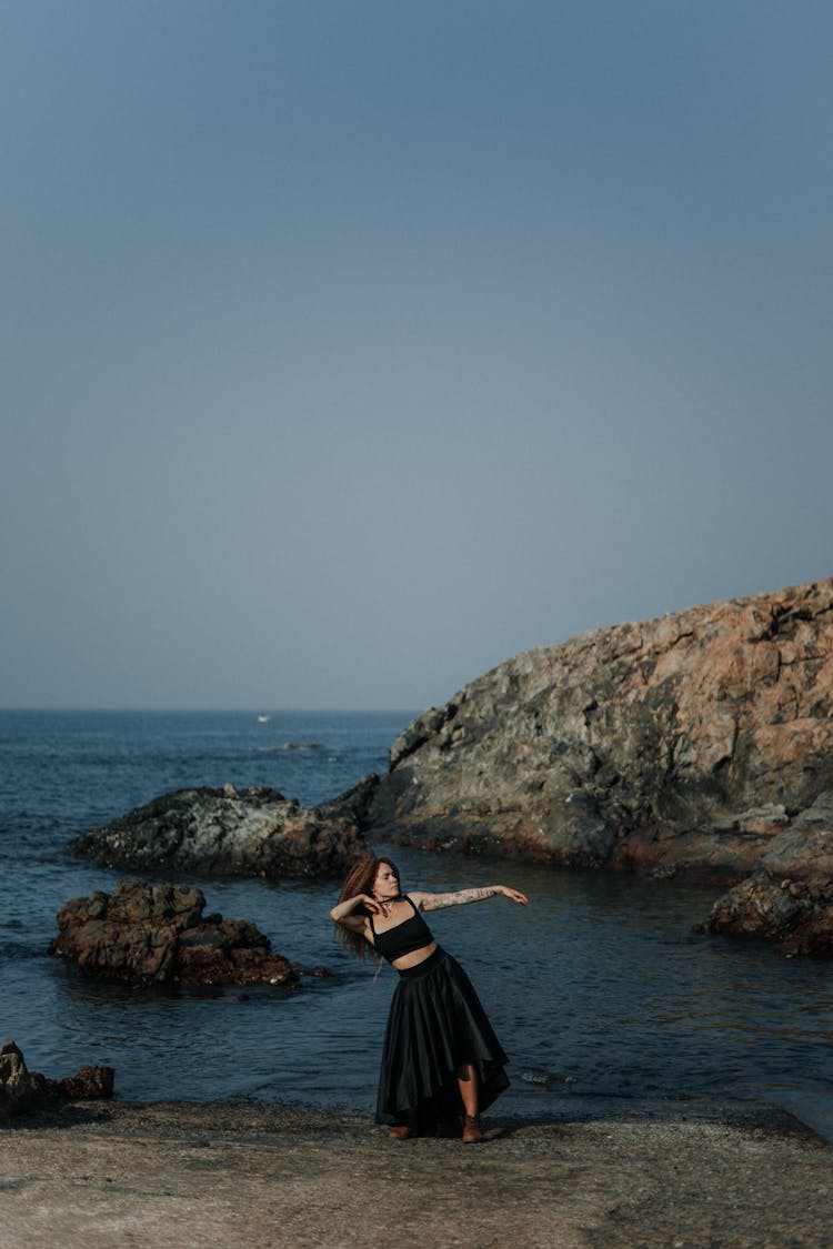 Woman Posing In Black Dress On A Beach 