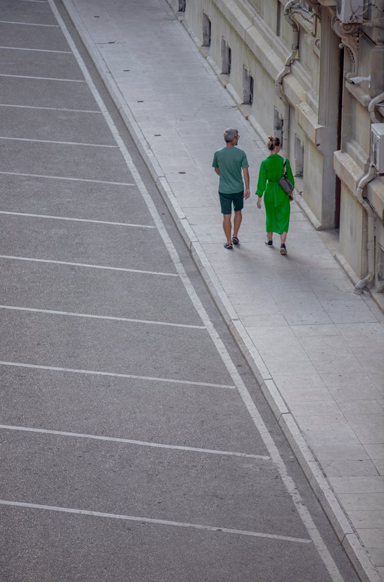 High Angle View Of A Couple Walking Down A Sidewalk 