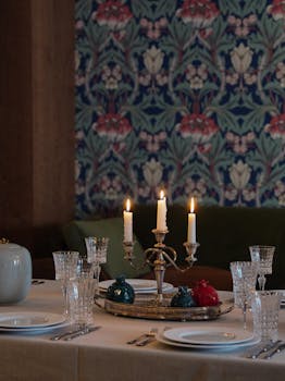 Candlelit dinner setting with elegant tableware and ambient wallpaper for a cozy atmosphere.