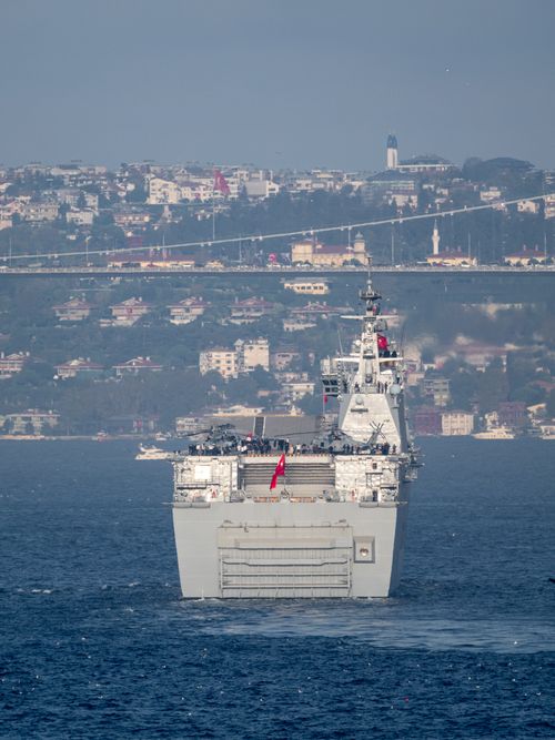 Free A military vessel cruising through Istanbul's Bosphorus Strait during daylight with cityscape in the background. Stock Photo