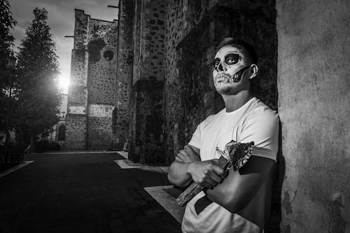 A Man in Makeup for the Day of the Dead in Mexico Standing Outside at Night and Holding an Axe