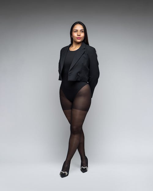 Brunette Woman Posing in Black Cropped Blazer, Bodysuit, and Tights