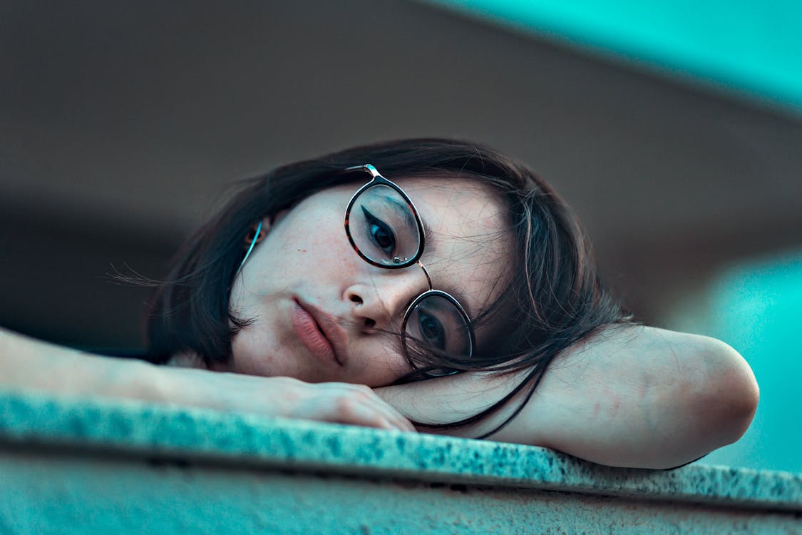 Free Photo of Woman in Eyeglasses Resting Her Head on Arm Stock Photo