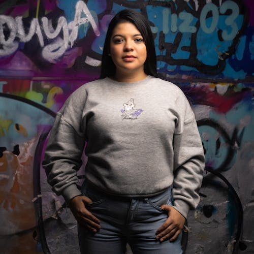 Brunette Woman in Gray Sweatshirt and Blue Jeans Posing by a Wall with Graffiti