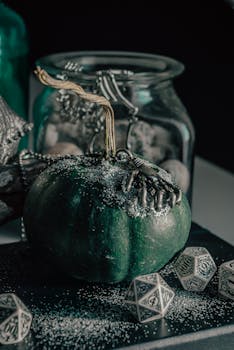A decorative green pumpkin adorned with silver accents, surrounded by polyhedral dice in an artistic close-up