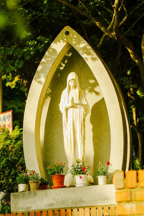 A Religious Statue of Virgin Mary in a Park in Sunlight 