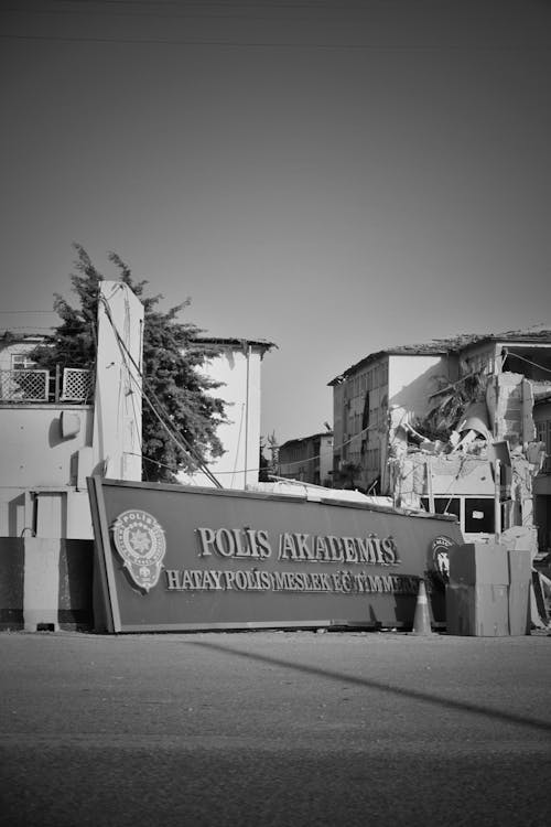 Hatay Police Academy Sign Lying on a Road near Damaged Building, Turkey