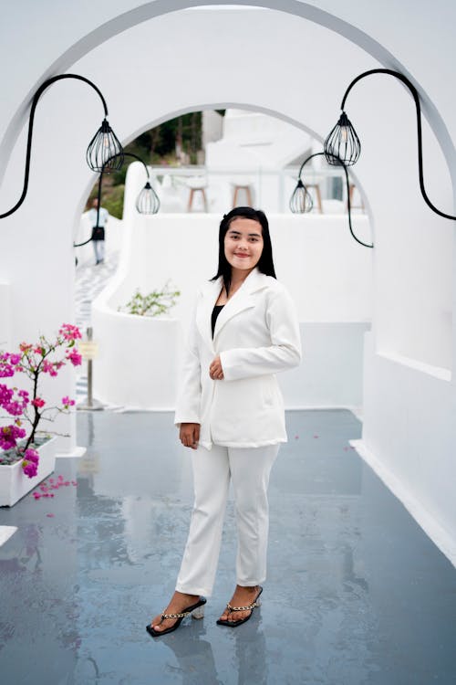 Young Elegant Woman in a White Suit Standing in an Archway 