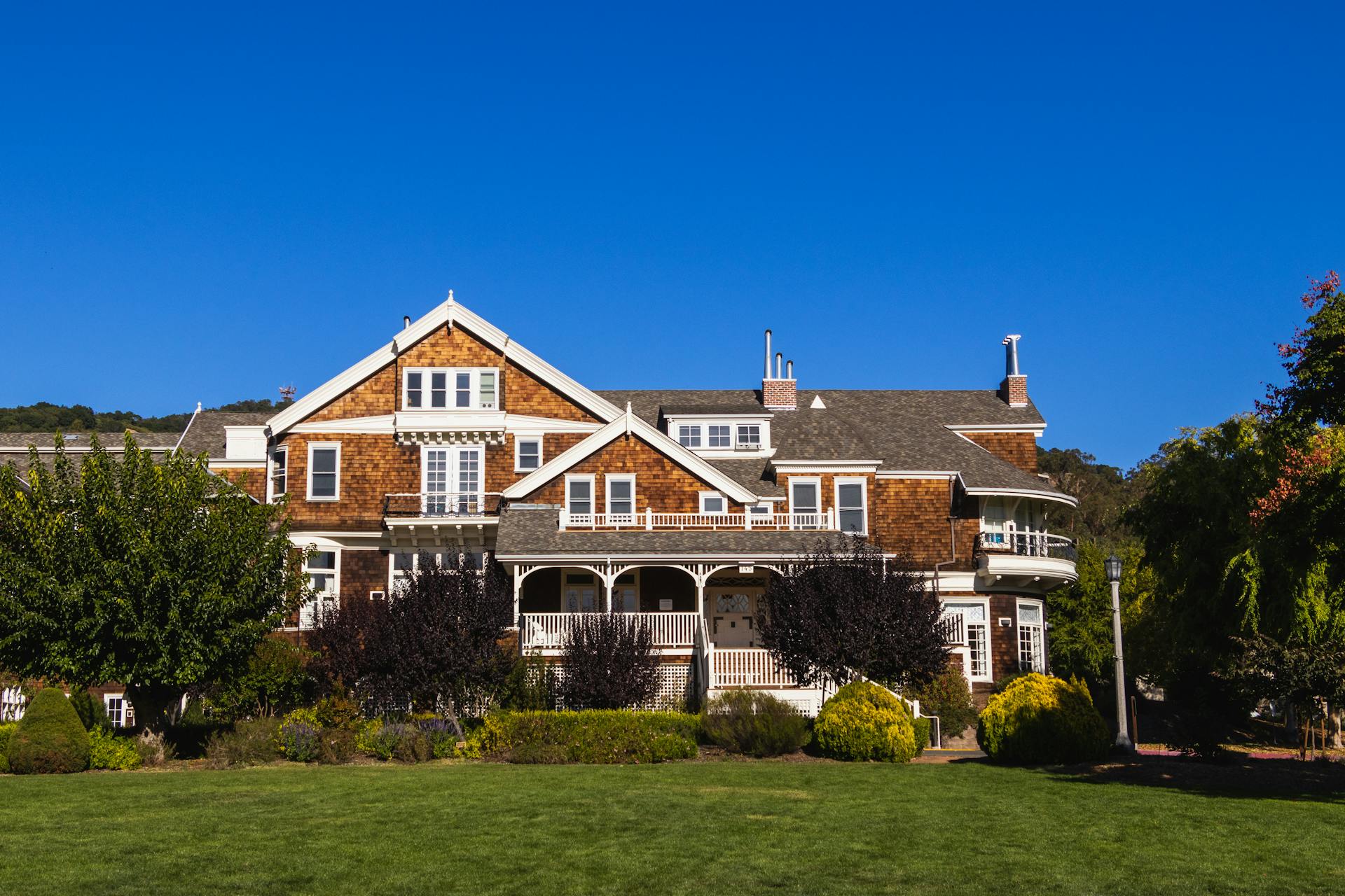 A beautiful, sunlit country home with a lush lawn and clear blue sky.