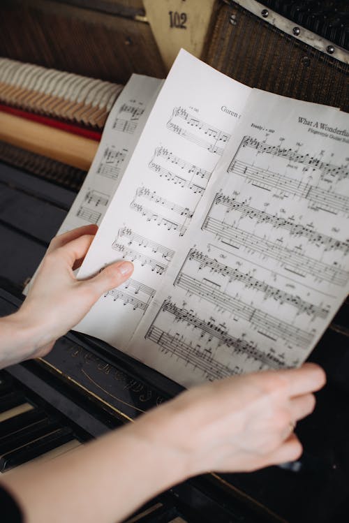 Woman Turning Pages of Sheet Music at a Piano