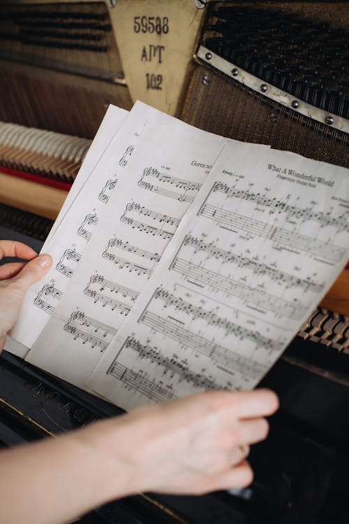 Woman Shuffling Pages of Sheet Music at a Piano
