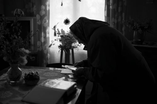Free A senior woman wearing a headscarf examines a photo album at home in Lithuania. Stock Photo