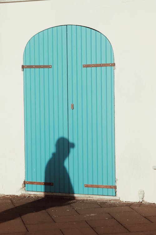 Shadow of a Man Wearing a Cap on Blue Door of a Building