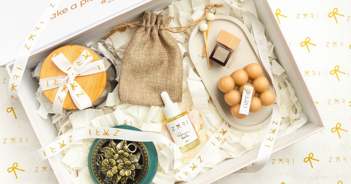 Elegant self-care gift box with candle, bottles, and wooden accessories on patterned wrapping paper