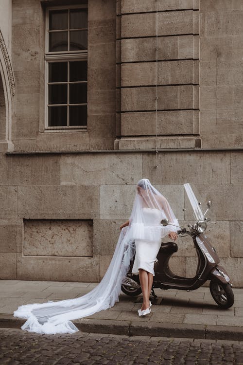Bride in a Long Veil and Midi Wedding Dress By Her Scooter Parked on the Sidewalk