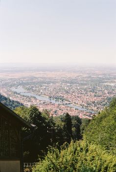 Panoramic aerial view of a cityscape featuring a river surrounded by green hills.