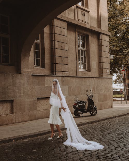 Free Bride Dragging Her Long Veil on Cobblestone in the Street Stock Photo