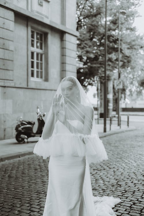 Bride Covered With Chiffon Veil Standing on Cobblestone Street