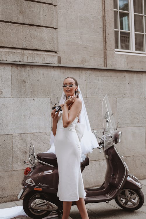 Bride in Sunglasses Talking on a Retro Phone Next to Vespa Scooter