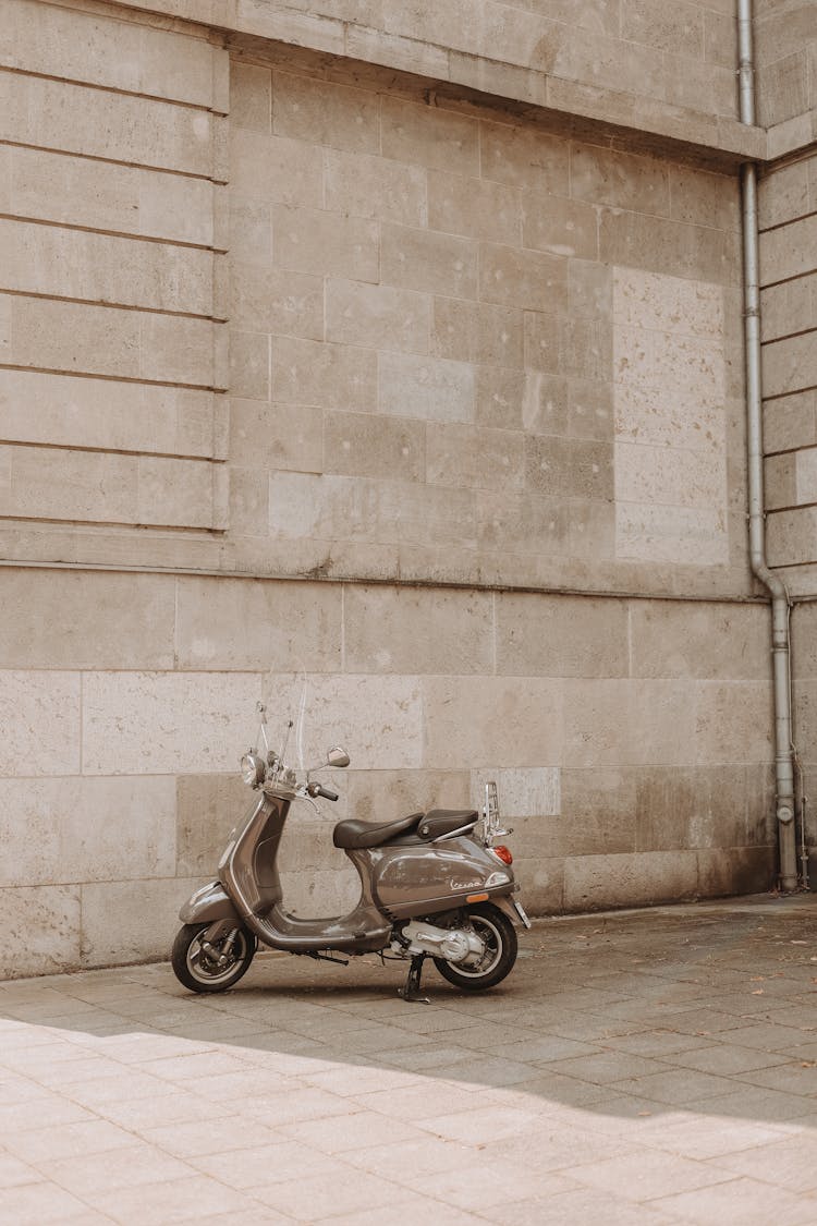 Gray Vespa Scooter Parked On The Sidewalk