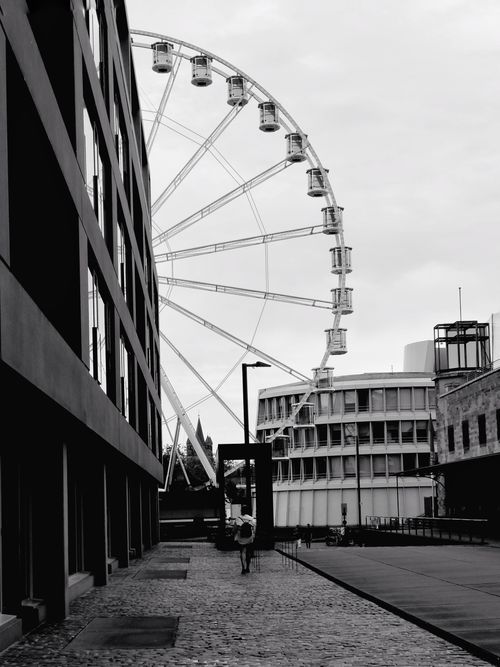 Free Monochrome photo of an urban street with a ferris wheel. Captured in Cologne, Germany. Stock Photo