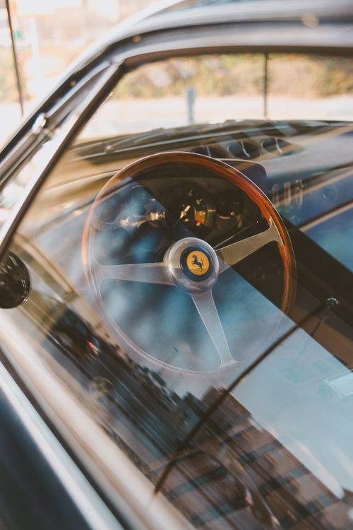 Free Elegant interior of a classic Ferrari car showcasing a wooden steering wheel with smooth reflections. Stock Photo