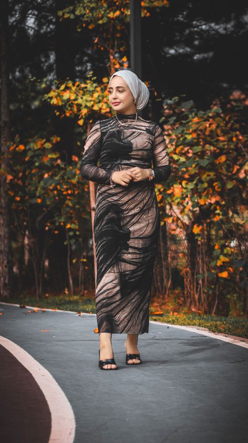 Free A woman in a hijab elegantly poses on a forest path amid autumn foliage. Stock Photo
