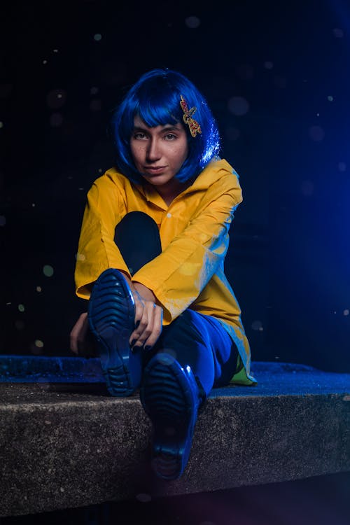 Model with Blue Hair Sitting on Wall at Night