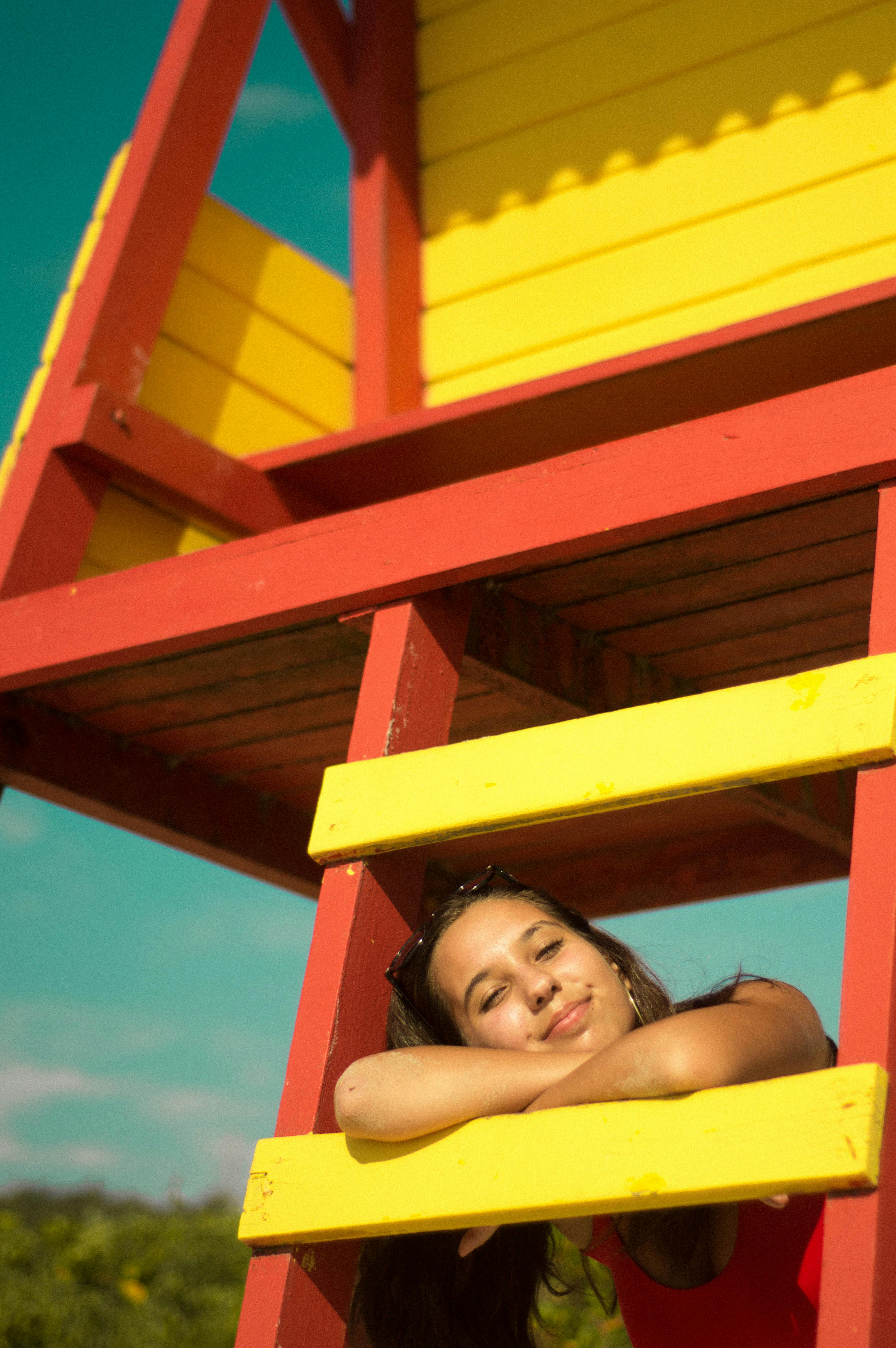 在海滩上色彩缤纷的救生塔旁，微笑的女人正享受着阳光明媚的一天