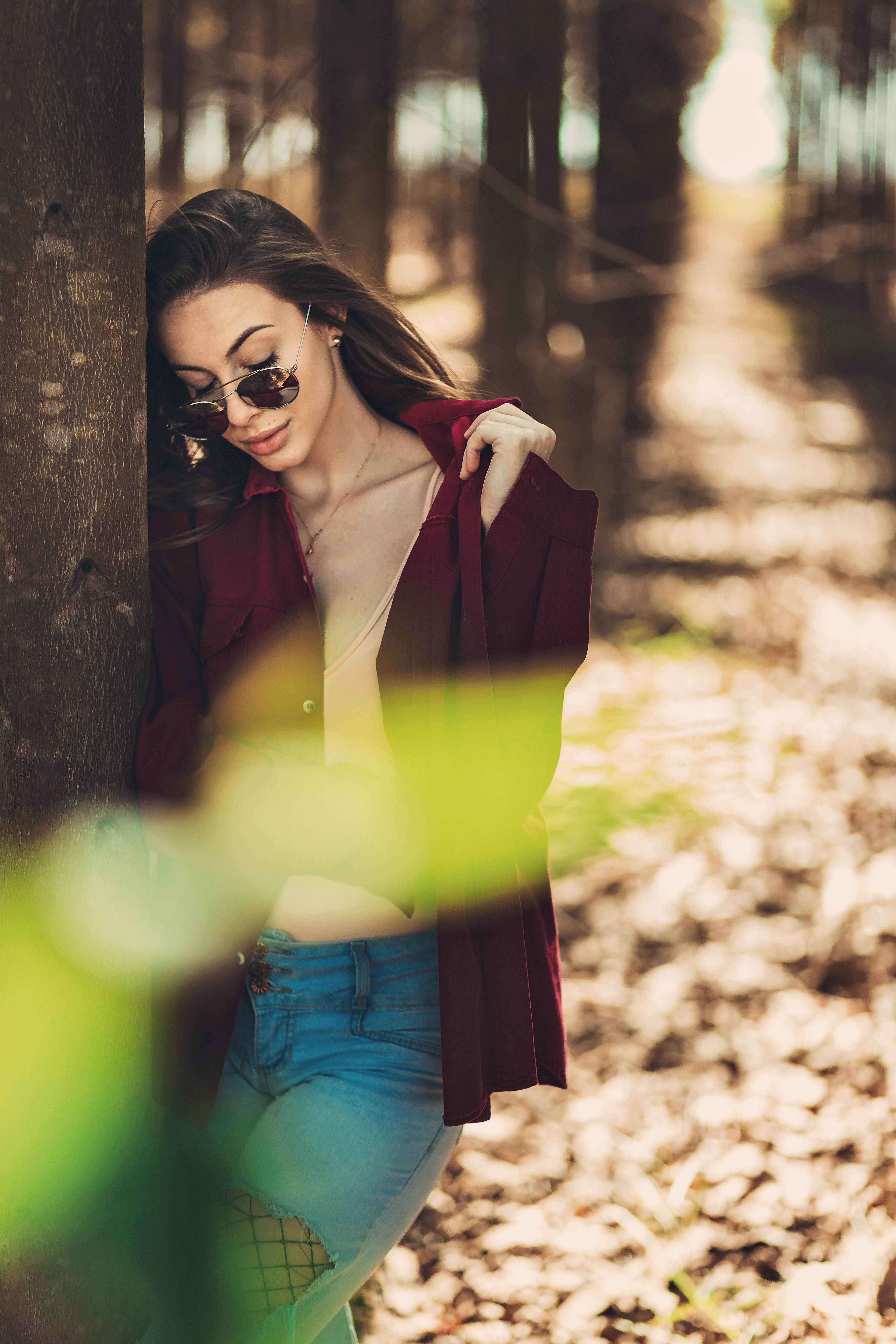 一位优雅的女士穿着休闲装，戴着太阳镜，在宁静的森林中摆姿势