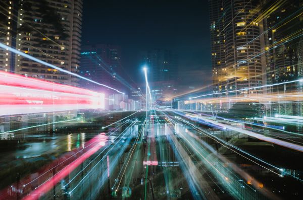 Paisagem urbana vibrante com deslumbrantes trilhas de luz e arranha-céus à noite.