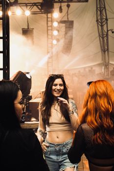 Group of young women enjoying a lively concert scene with bright lights and music.