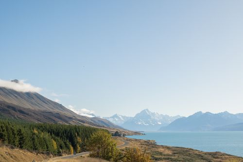 Free A scenic aerial view of a pristine mountain lake with snow-capped peaks and lush green forests. Stock Photo