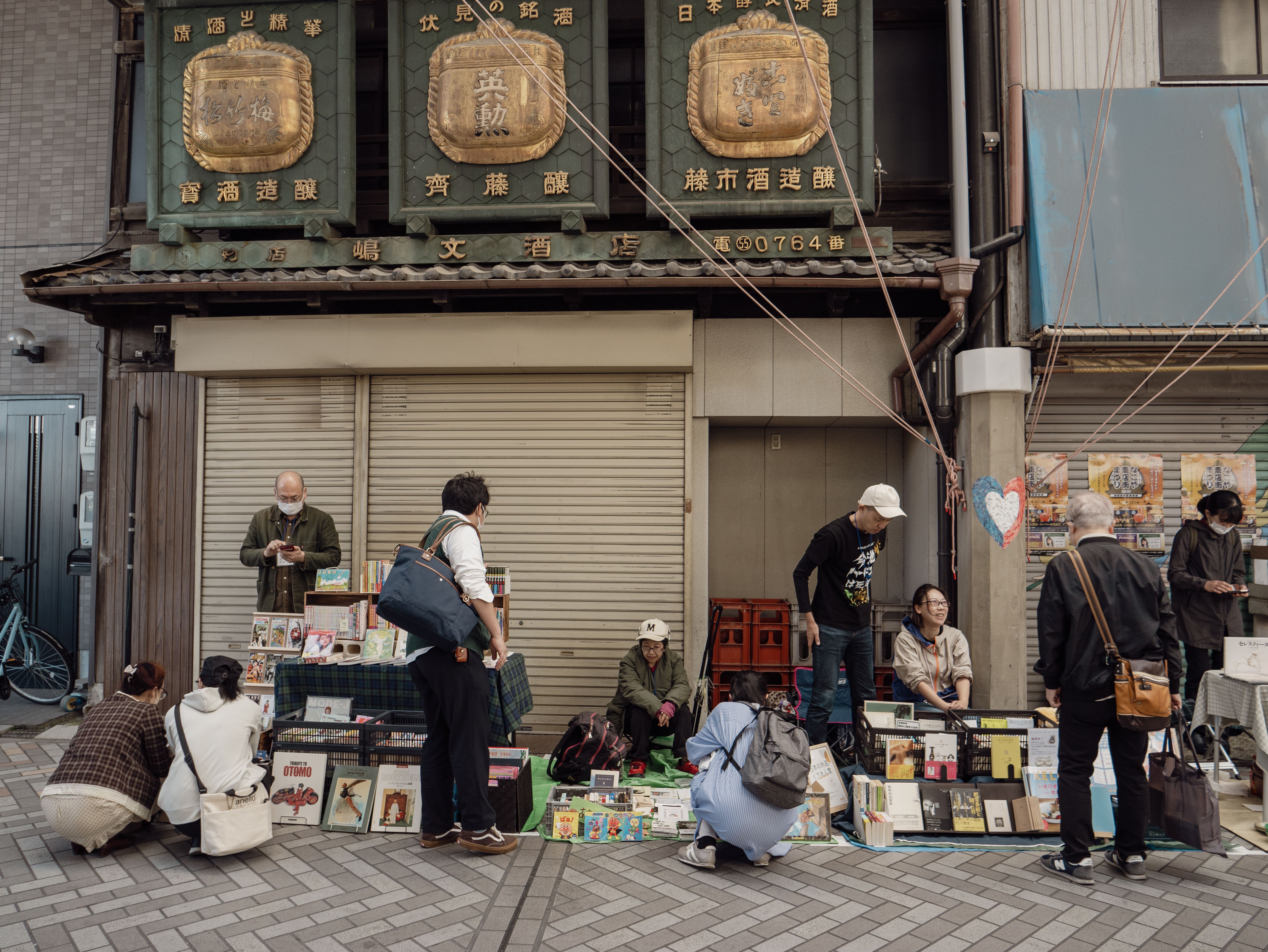 Explore the vibrant street market in Nagoya, Japan, with people shopping and mingling under ornamented signs.