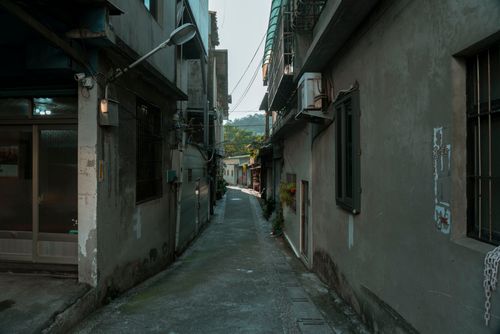 Free A quiet narrow alleyway surrounded by residential buildings, evoking an urban atmosphere. Stock Photo