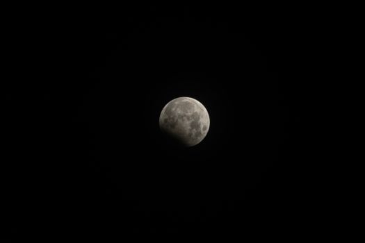 A clear view of the moon during a lunar eclipse with shadowed detail.