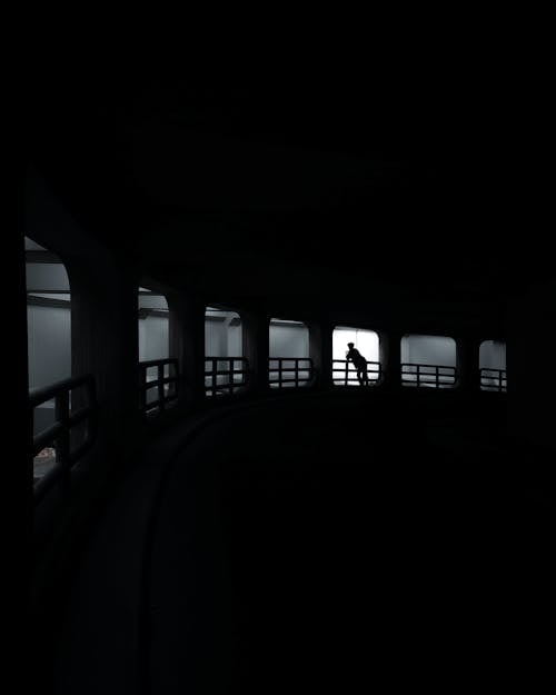 Silhouette of a Person Standing at the Railing of the Exit Ramp from the Parking Garage