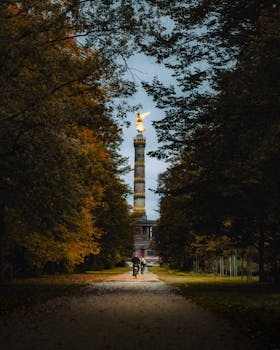 Scenic view of Berlin's Victory Column surrounded by autumn foliage in a city park.