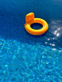 A bright yellow swim ring floating in a sunlit swimming pool, showcasing summer vibes.