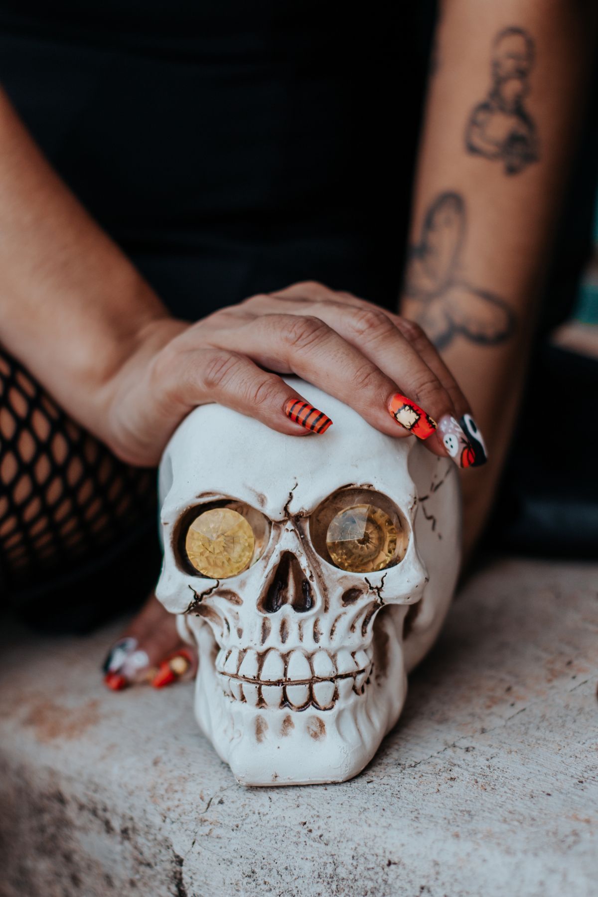 Close-up of a decorated skull being held by a tattooed hand, perfect for Halloween themes.