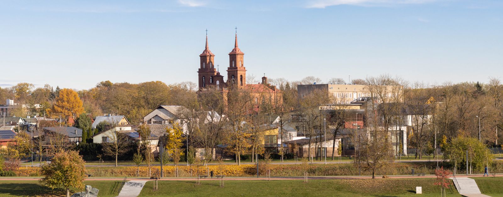 A picturesque aerial view of Panevėžys, Lithuania featuring a historic church and autumn foliage.
