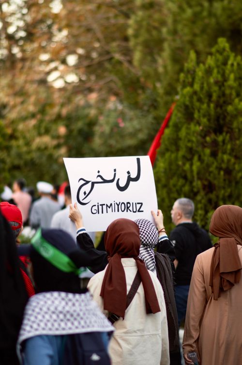 Free Individuals participating in a peaceful protest in İstanbul, Türkiye, holding a sign with Arabic and Turkish text. Stock Photo